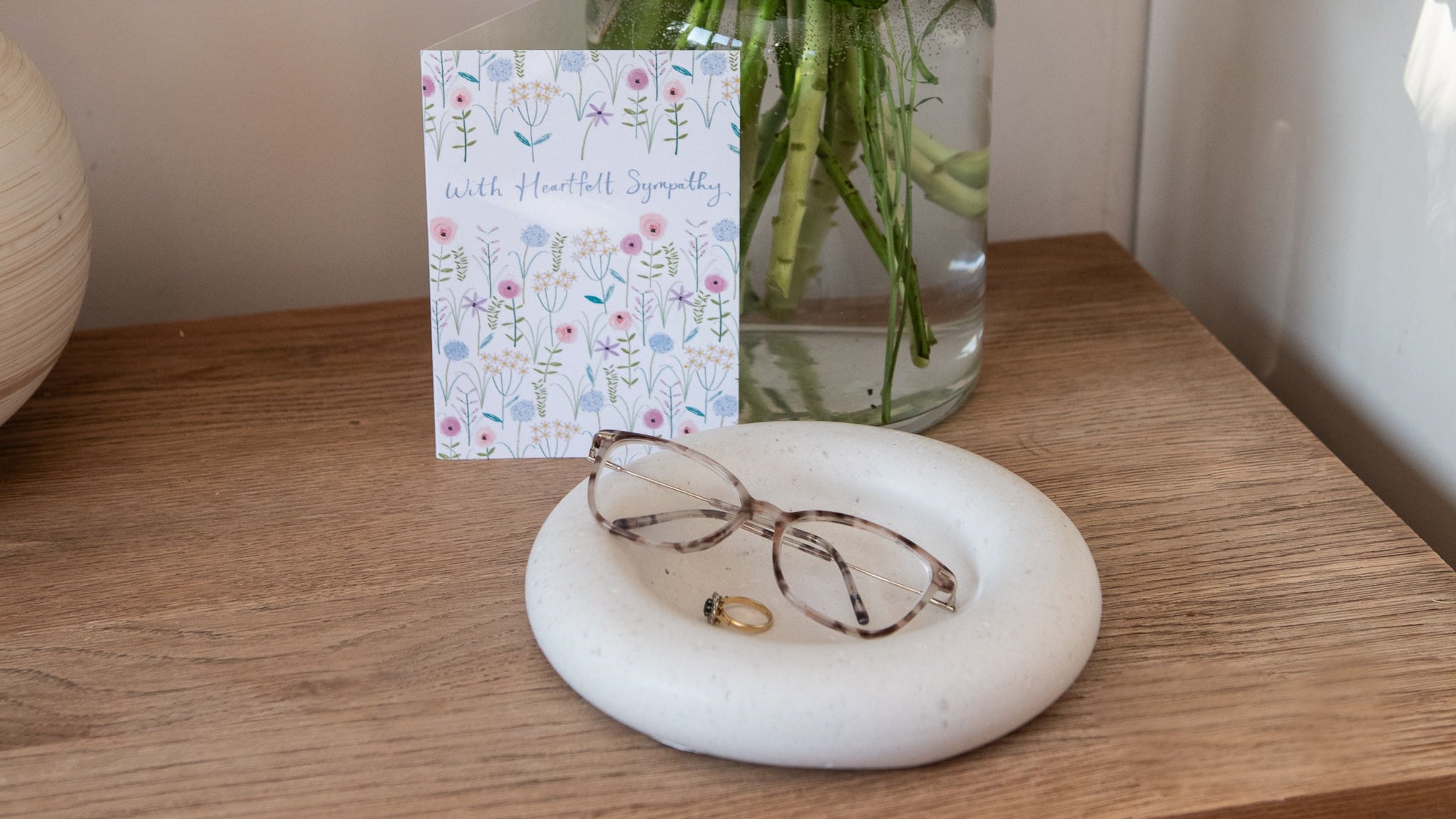 A trinket bowl made from human or pet ash with a sympathy card and vase